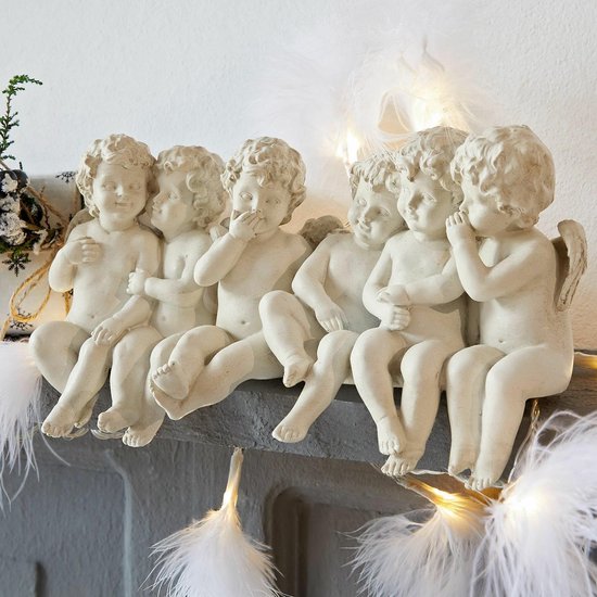 Zes witte cherubijnbeeldjes zitten op een grijze rand, versierd met veren en kerstverlichting.