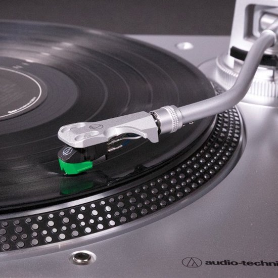 Detailopname van de toonarm met groene naald op een vinylplaat.