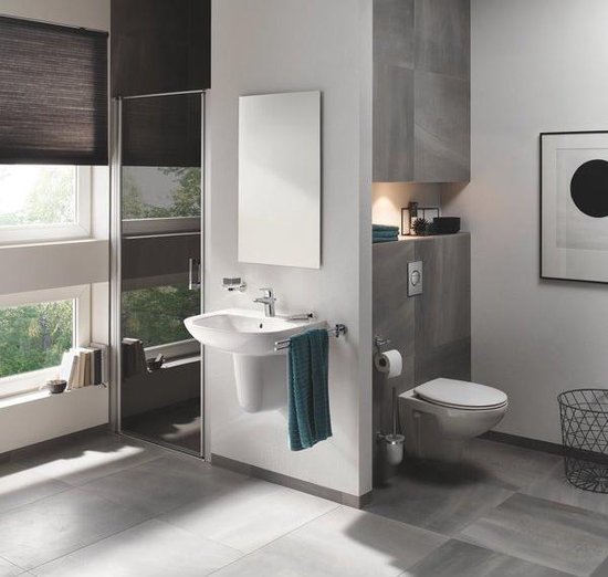 Toiletborstel naast een witte toiletpot in een moderne badkamer.