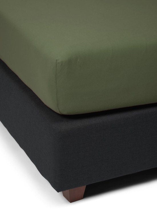 Een mosgroen jersey hoeslaken gestapeld op een donkergrijs boxspring.