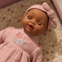 Close-up van het gezicht van babypop Yara in roze outfit, met gesloten oogjes.