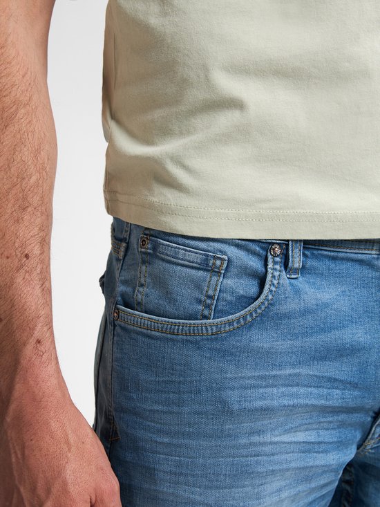 Detail van de heupzak van een lichtblauwe jeans met subtiele naden.