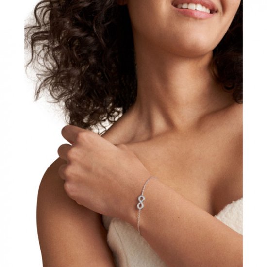 Vrouw met een zilverkleurige schakelarmband met een infinity symbool bezet met steentjes.