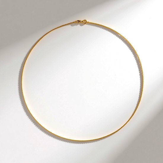 Goudkleurige, fijne ketting met een cruncheffect, liggend op een witte ondergrond.