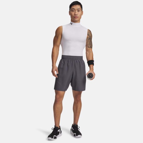 Man in grijze sportbroek en wit mouwloos shirt met hoge hals, witte schoenen.