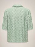 Achterkant van een lichtgroene blouse met broderie anglaise, korte mouwen en een kraagje.