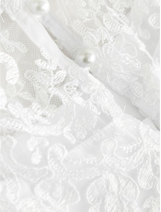 Sluiting van witte jurk met parelmoeren knopen en bloemenkant overlay.