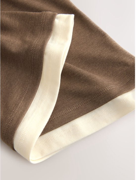Detail van de zomen van een bruin T-shirt met crème rand.