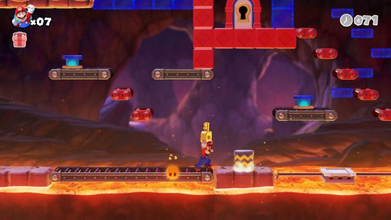 Mario speelt in een grot met platforms boven lava. Hij springt over een vijand.