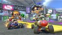 Twee Splatoon-personages racen in karts op een baan met gele lijnen en oranje objecten.