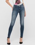 Model in een blauwe skinny jeans met rafels aan de zoom, gedragen met hoge hakken.