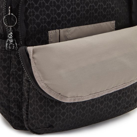 Detail van zwarte rugzak met beige klep en sleutelhanger.