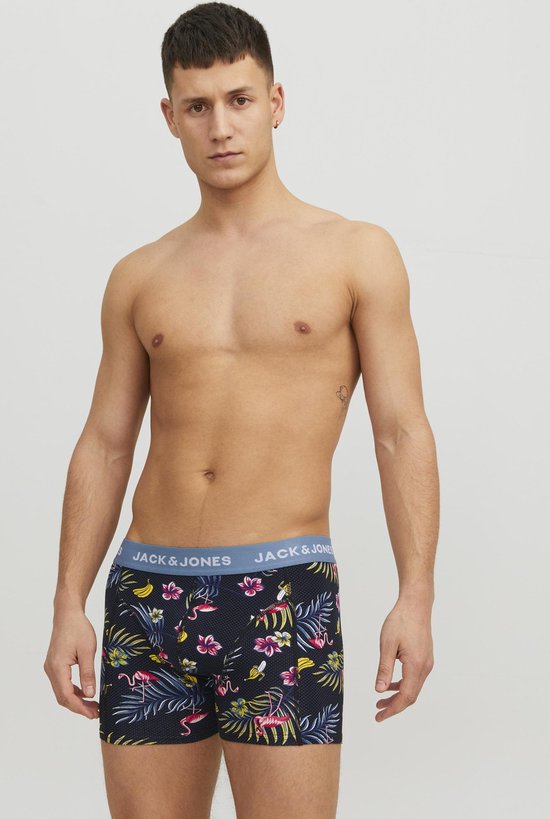 Model draagt boxershorts met donkerblauwe print van roze flamingo's, bananen en tropische bloemen. Lichtblauwe tailleband met JACK & JONES.