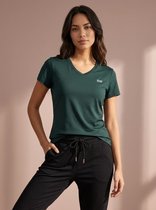 Vrouw met een smaragdgroen sportshirt met V-hals en een logo op de borst.