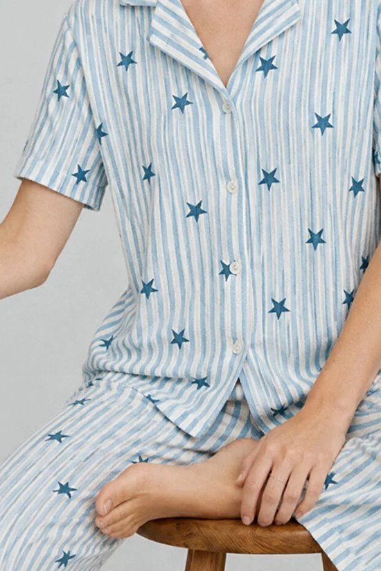 Detailopname van pyjamashirt met knoopsluiting en sterrenpatroon op een wit-blauw gestreepte stof.