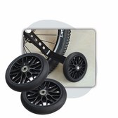 Detailopname van zwarte zijwieltjes bevestigd aan het frame van een kinderfiets.