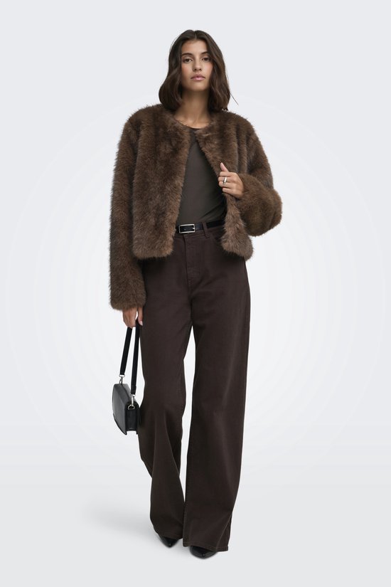 Model in een volledige outfit met bruine jas van imitatiebont, donkerbruine broek en zwarte tas.