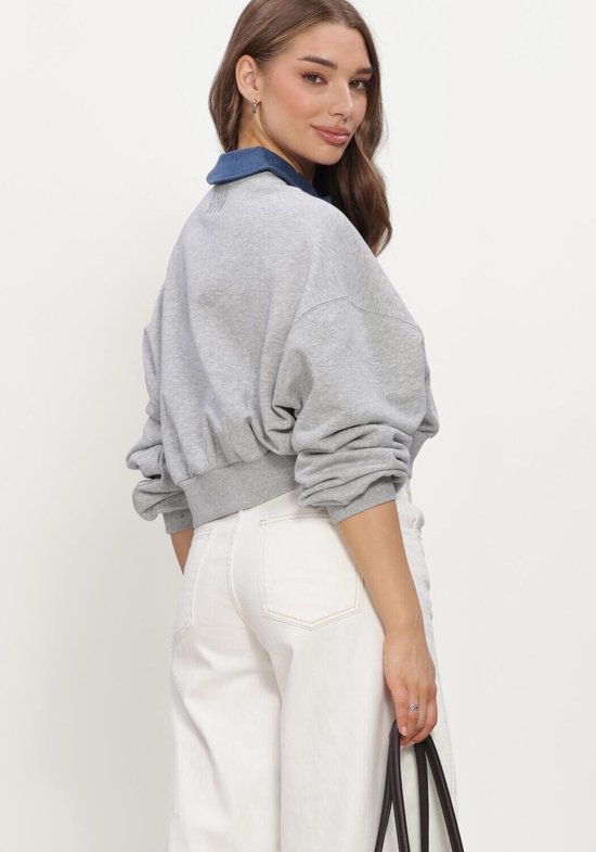 Achteraanzicht van een grijze crop sweater met een blauwe kraag, gedragen op een witte broek.