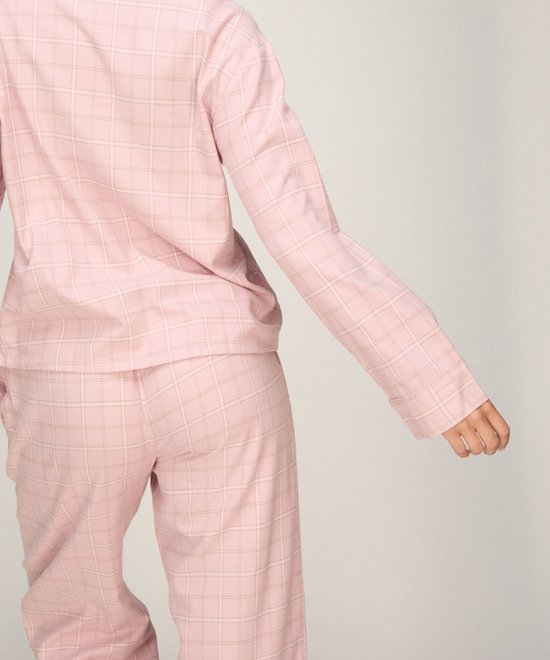 Model van achteren gezien in roze geruite pyjamabroek en shirt.