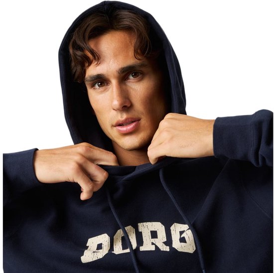 Close-up van een donkerblauwe hoodie met crèmekleurige 'BORG' tekst, de capuchon wordt door de man aangetrokken.