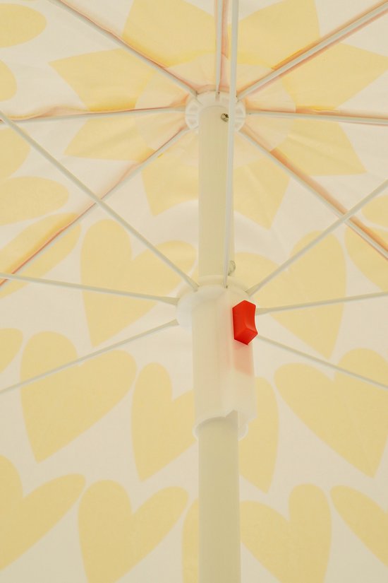 Close-up van een parasol met een patroon van gele hartjes, met een rode knop op de witte stang.