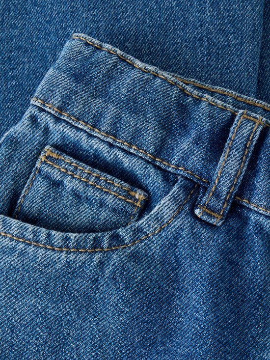Detailopname van de blauwe spijkerbroekzak met contrasterende goudkleurige stiksels.