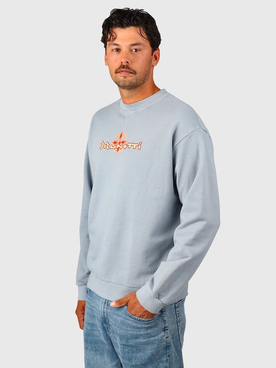 Model draagt een lichtblauwe Brunotti sweater met een oranje-rood logoprint op de borst.