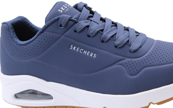 Close-up van de marineblauwe Skechers sneaker met vetersluiting, perforaties en wit zijlogo.