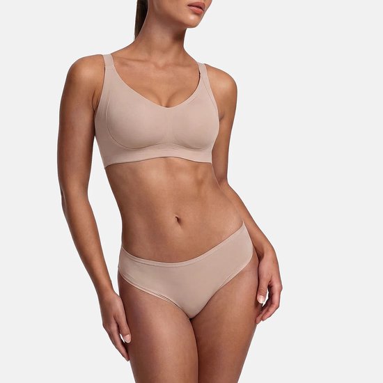 Model draagt een naadloze, beige beha en bijpassend slipje met een comfortabele pasvorm.