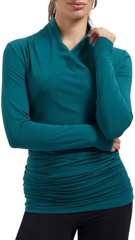 Model met blauwgrijze longsleeve, wikkelkraag en gedrapeerde buik.