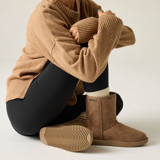 Bruine suède laarzen met beige gebreide beenwarmers en zwarte legging. De zool van één laars is te zien.