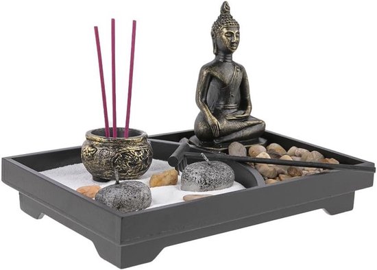 Zen tuin met Boeddhabeeld, wierookhouders met rode wierookstokjes, stenen en een harkje.
