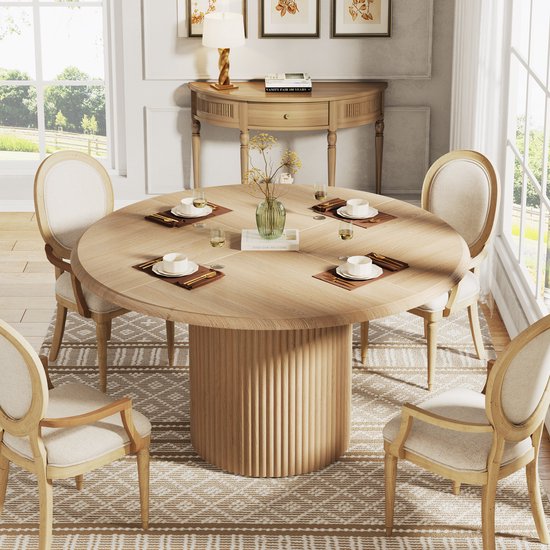 Ronde eettafel met houten visgraatblad en gecanneleerde poot, gedekt met placemats, servies en glazen.