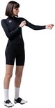 Model in zwart wieleroutfit met lange mouwen en korte broek, dat armstukken aantrekt.