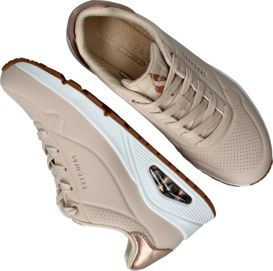 Deux baskets Skechers couleur naturelle avec détails dorés au talon, semelles blanches et amorti air.