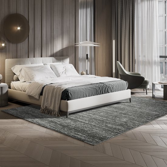 Een grijs vloerkleed met een abstract patroon, deels bedekt door een bed met wit beddengoed en een grijze sprei.