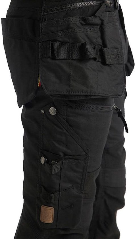 Detail van een zwarte werkbroek met gespen, ritssluitingen en extra zakken.