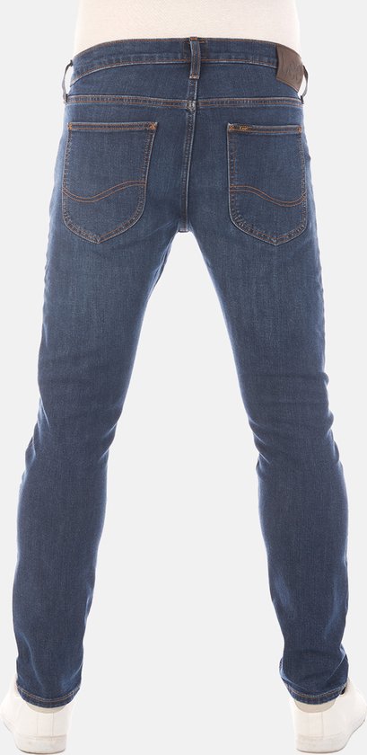 Achterkant van een man in een donkerblauwe jeans met oranje stiksels en een bruin Lee-label.