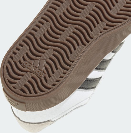Bruine buitenzool met Adidas-logo en golvend profiel onder een witte sneaker.