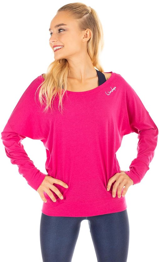 Model in een roze longsleeve met wijde boothals, logo links op de borst, en een donkerblauwe sportbeha eronder.