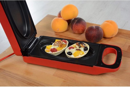 Rode grill met open deksel, met twee toetjes gevuld met fruit zoals aardbeien, bessen en perziken.