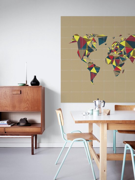 Carte du monde abstraite aux polygones multicolores, accrochée dans une salle à manger au-dessus d'une commode en bois.