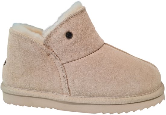 Zijkant van een beige suède slipper met schapenvacht voering en een bruin 'Warmbat' metalen detail.