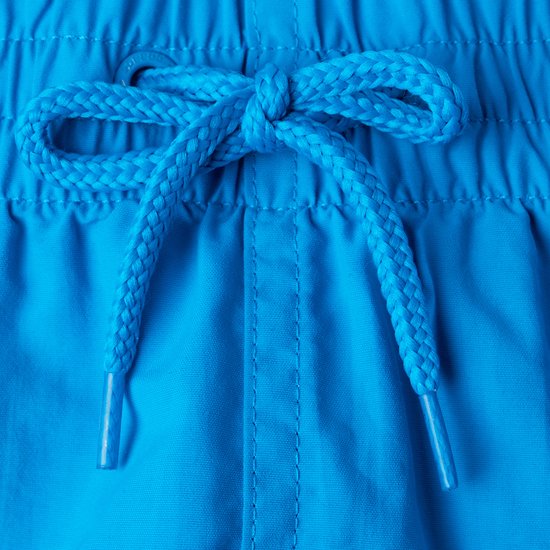 Détail du nœud d'un short de bain bleu.