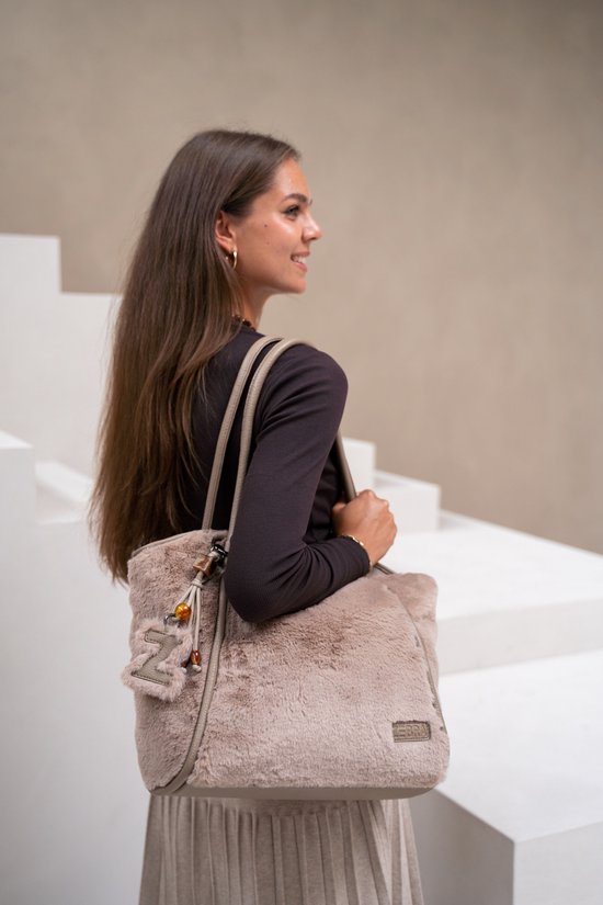 Model met bruine tas met lichtbruine vacht, beige handvatten en bag charm.