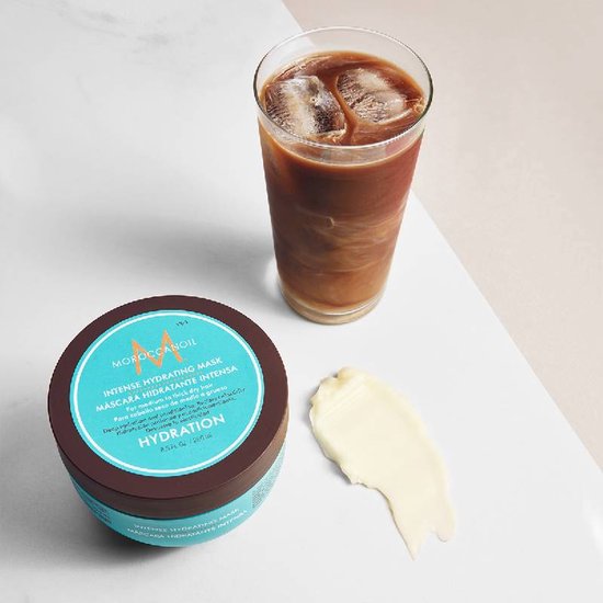 Bruine Moroccanoil pot met turquoise label, naast een glas ijskoffie en een klodder crème.
