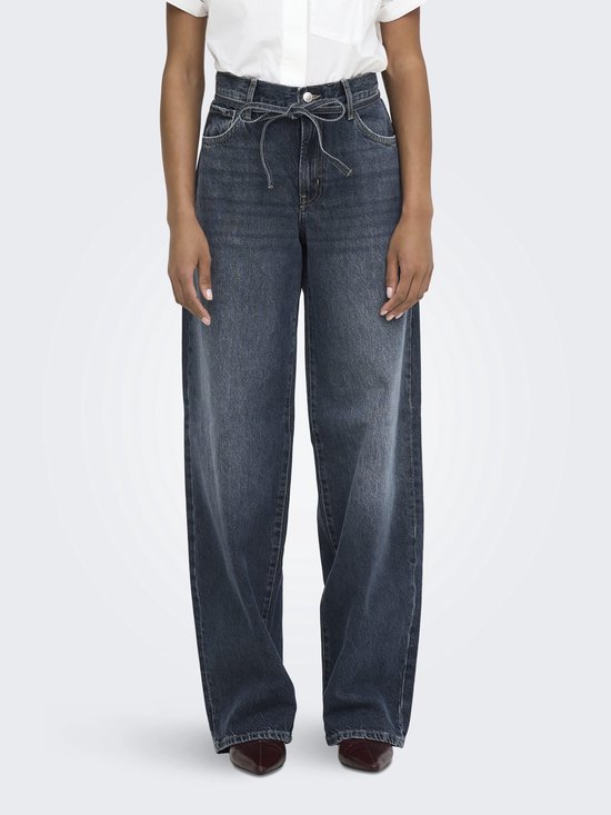 Donkerblauwe wijde jeans met strikceintuur. Model staat op witte achtergrond.
