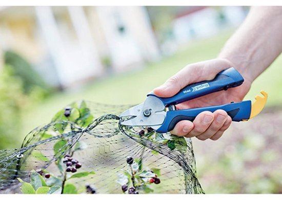 Hand met een blauwe Rapid FP20 hekwerktang die groen draad van een hekwerk knipt. Gele grijper aan de onderkant.