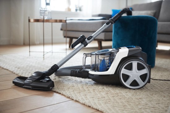 Aspirateur Philips PowerPro Compact sur un tapis dans un salon.