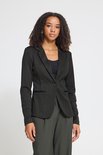 Model in een zwarte blazer met diagonaal patroon en één knoop, gecombineerd met een donkergrijze pantalon.